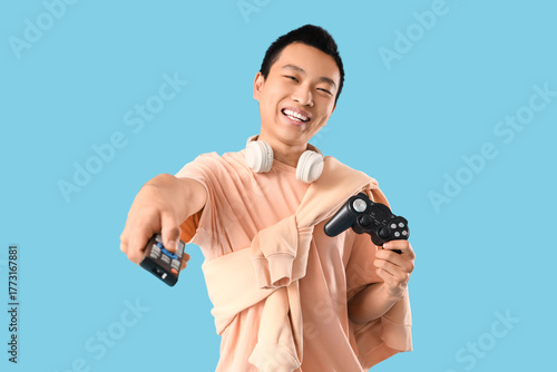 Young Asian man with TV rem...