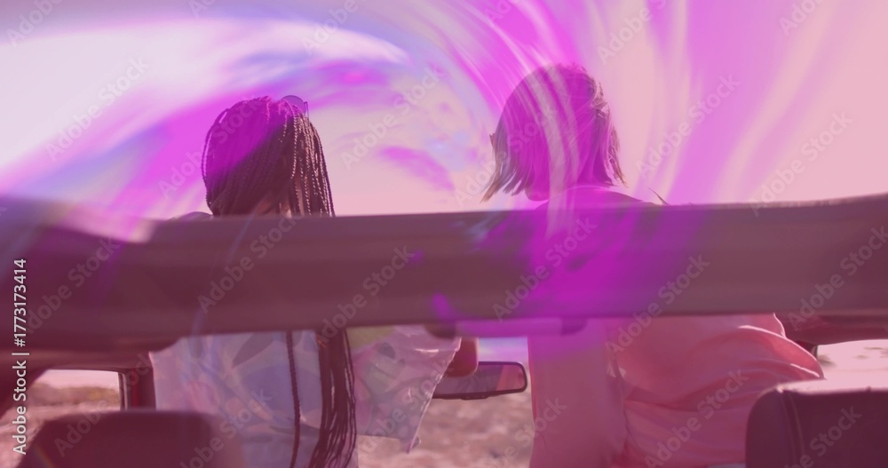 Fotografija Friends leaning forward in convertible car at desert roadside at sunset, with pu