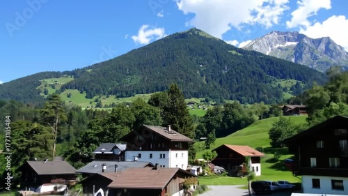 Wallpaper Mural Charming Alpine Village Nestled Amongst Lush Green Hills Under a Majestic Mountain Peak Under a Clear Blue Sky Torontodigital.ca