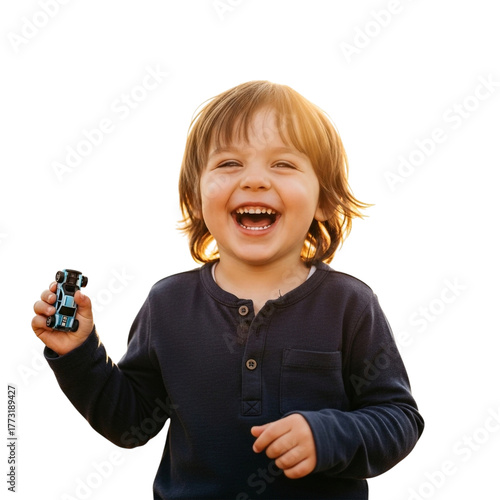 Happy child laughing, holding a toy car, with golden hour lighting.