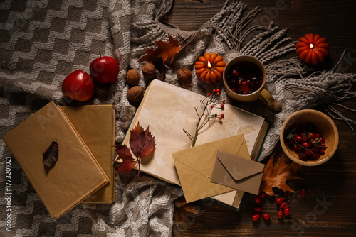 Fototapeta Naklejka Na Ścianę i Meble -  Books with cup of tea, fruits, envelopes, scarf and autumn decorations on brown wooden background