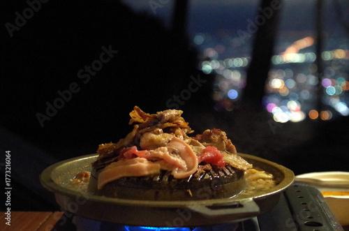 Grilled pork, grilled pork, camping food on the mountain, view of city lights, seen from a high angle