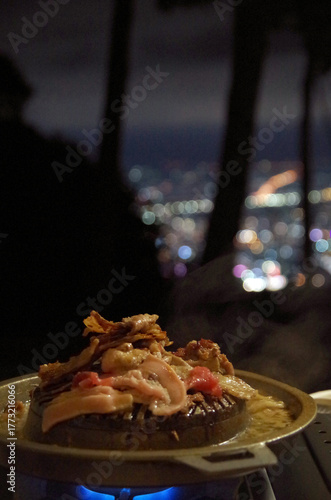 Grilled pork, grilled pork, camping food on the mountain, view of city lights, seen from a high angle