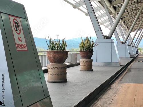 Modern Airport or transit terminal entrance with No Parking Sign, potted plants, and mountain view.