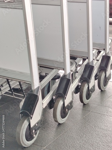Transportation equipment, wheels and casters of multiple metal baggage carts lined up.
