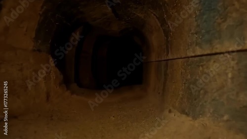 Eerie tunnel with sandy floor and walls, leading into darkness. Mysterious.