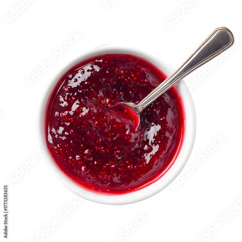 Bowl of raspberry jam with a spoon, top view. Sweet berry preserve or marmalade isolated on a black background for breakfast.
