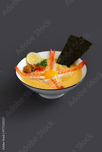 Ramen noodle in spicy broth with Shrimp, fresh green onions, Nori and egg yolk in bowl.