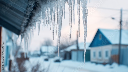 Close-up of icicles hanging from roof with snowy landscape and houses in