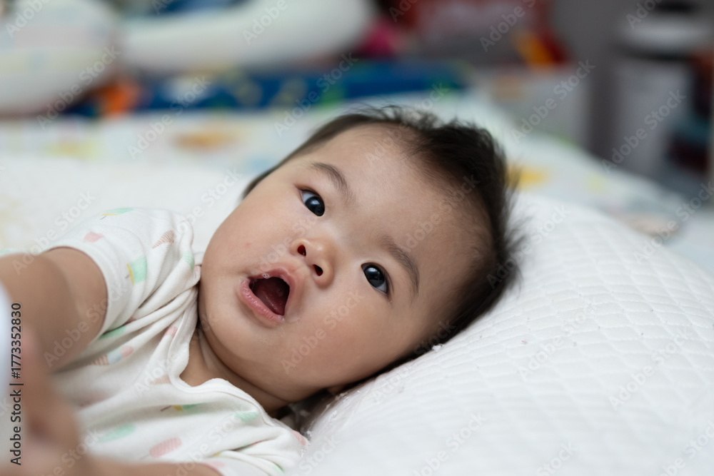 Fototapeta premium Adorable baby girl is lying on a bed after drinking milk