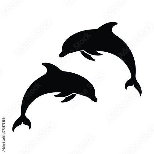 Two silhouetted dolphins leaping and swimming together in the ocean