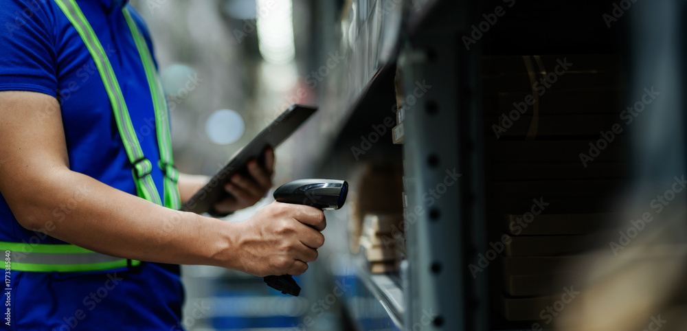 Naklejka premium A man in a blue shirt is using a barcode scanner to scan a product. Concept of efficiency and productivity, as the man is using technology to quickly and accurately identify the product