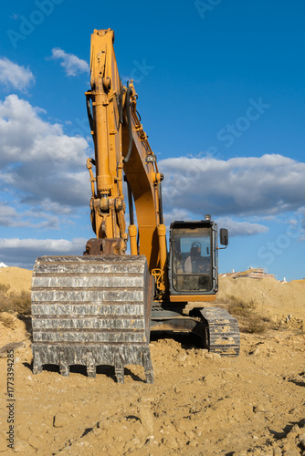 large yellow excavator working on the construction site moving earth