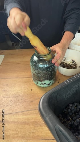 A man crushes grapes with sugar in a jar Making homemade wine at home. Vertical video.