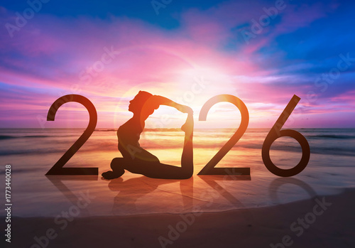 Happy new year card 2026. Silhouette of healthy girl doing Yoga One Legged Pigeon pose on tropical beach with sunset sky background, woman practicing yoga as a part of the Number 2026 sign.