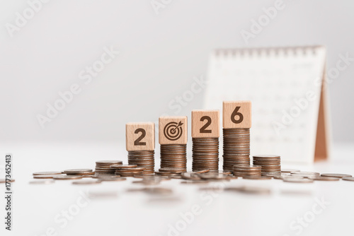 Stacks of coins with Calendar and wooden blocks forming number 2026 for target financial growth, investment planning for money savings, business goals concept. Budget and tax, Happy new year 2026
