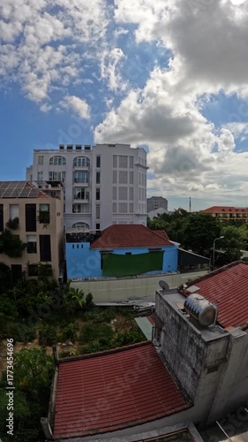 Smooth timelapse of light clouds drifting above urban buildings in Hoi An, Vietnam, capturing the blend of city life and calm tropical cloudy sky.