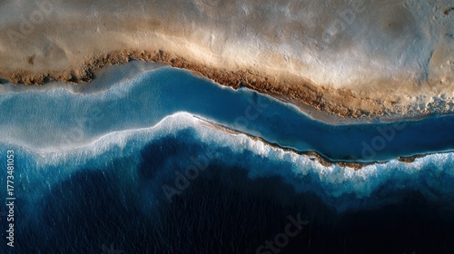 Top-down aerial view of a vibrant blue ocean meeting salt-crusted shore.