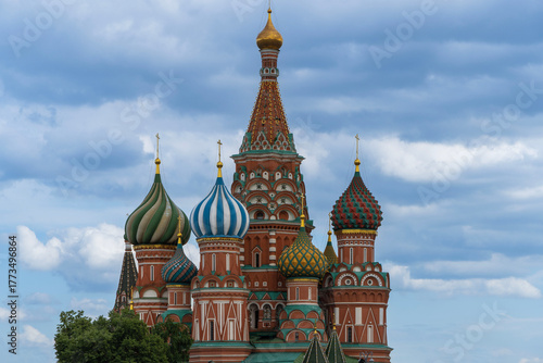 View of Orthodox St. Basil's Cathedral from Red Square. Multi-colored domes with Orthodox crosses rise above towers of cathedral. Walls of cathedral are made of red brick