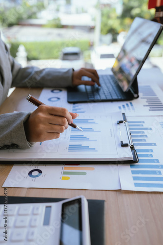 Businesswoman analyzing financial charts and data reports with a laptop at the office, planning strategy and performance review.