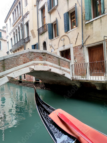 Gondola on a calm Venice canal beside a historic brick bridge and shuttered facades