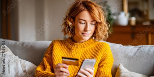 Caucasian woman in cozy sweater making online transaction on her smartphone at home