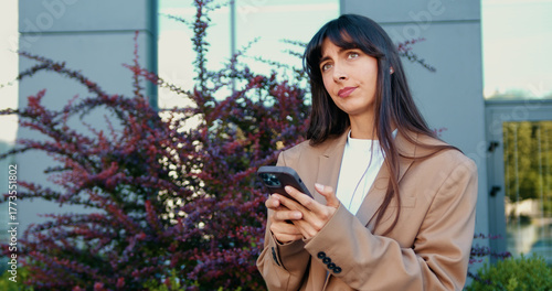 Konstfotografi Portrait of disappointed businesswoman holding smartphone, frowning after receiving bad news, showing frustration outdoors near office building