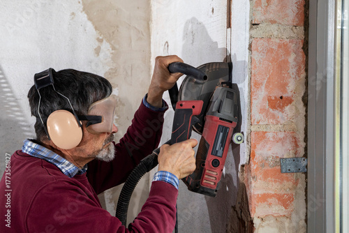 Construction Worker using a Wall Chaser to make Channels for Electric Installation