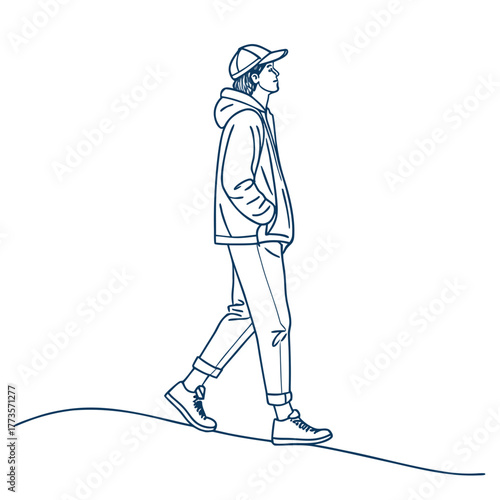 Young man walking casually in hoodie and cap on a path  