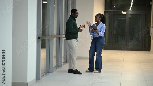 African american colleagues discussing business in an office hallway