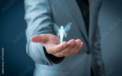 Professional business photo of a hand in a gray suit and blue striped tie reaching out to touch a glowing white digital human icon in a circular translucent frame against a dark blue blurred backgroun
