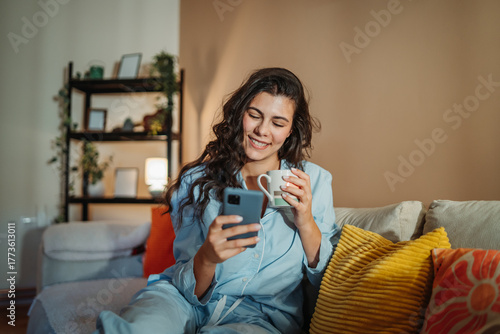 Young woman enjoying a cozy morning at home with coffee and smartphone