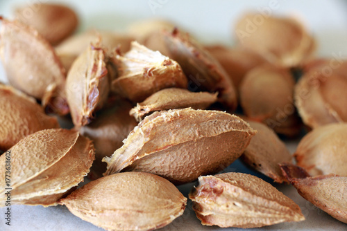 Top-view photo of apricot kernels arranged in a wooden bowl on a dark background. Ideal for food, organic produce, healthy lifestyle, and nutrition concepts