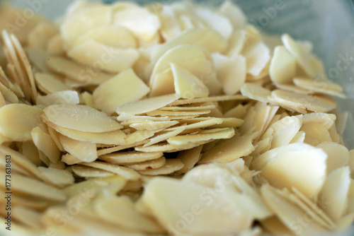 Close-up image of almond flakes in a wooden bowl on a dark textured background. High-quality food photography suitable for healthy eating, recipes, and nutrition themes.