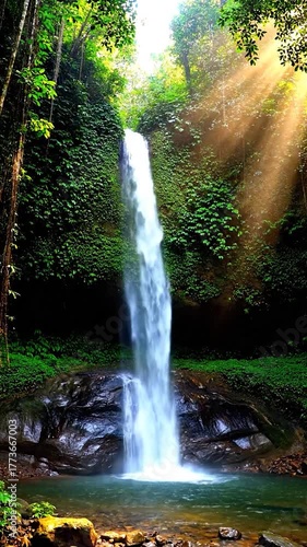 A majestic waterfall cascades into a tranquil pool surrounded by lush, green vegetation