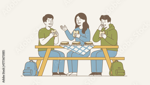 A group of friends gathered around a picnic table during lunch sharing sandwiches and laughter with their backpacks casually tossed nearby.