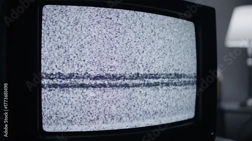 Static-filled retro TV screen with horizontal noise, blurred background with lamp