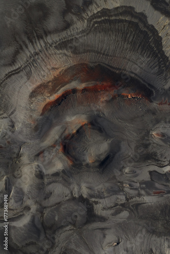 Aerial view of volcanic landscape, a tapestry of dark, rugged terrain interwoven with striking veins of red and orange earth, Highlands Of Iceland, Sveitarfélagio Hornafjorour, Iceland.