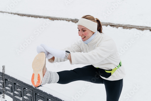 young caucasian woman doing stretching exercises before running in park in winter, white sports jacket, black trousers, active lifestyle concept, jogging in winter, sports life, copy space