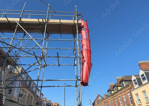 Polypropylene rubble chutes attached to scaffolding, to facilitate the disposal of rubbish during a property refurbishment project, on an urban street in England, UK.