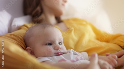 Mother napping on bed with active baby girl, showing tiredness and motherhood