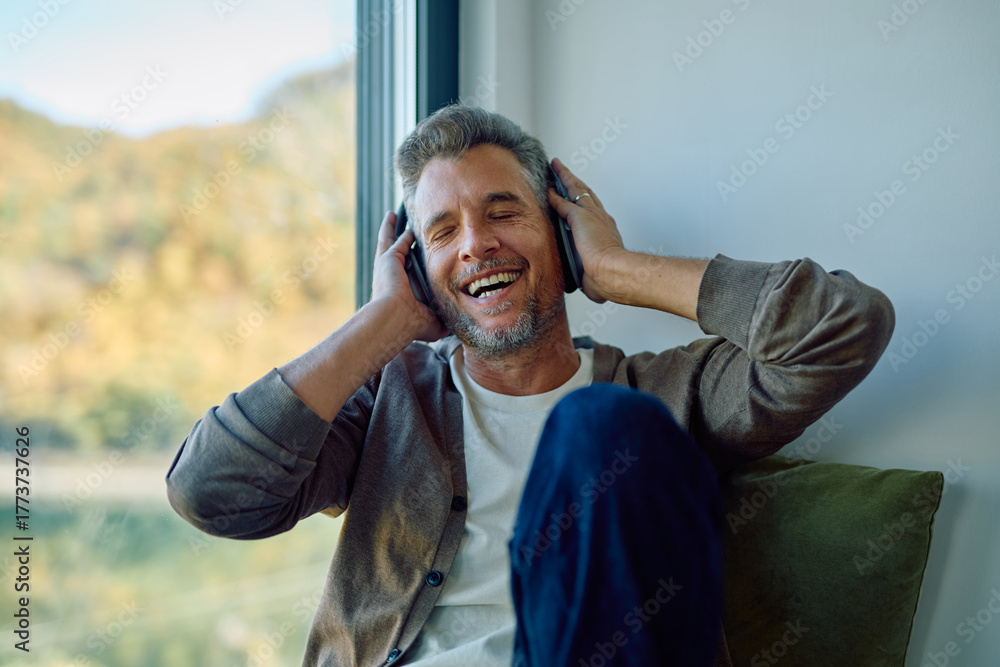 Φωτογραφία Mature man enjoying his favorite music with headphones, laughing cheerfully and