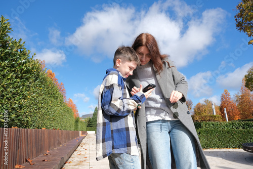 mother and son putting on new sunglasses in the street taking photos on the phone