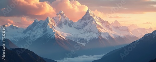 Majestic snow capped mountain peaks illuminated by golden sunrise sky with soft clouds. Layers of rugged terrain visible in distance. Serene natural high altitude landscape.