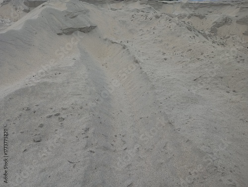 Vast expanse of granular sand dunes under natural daylight, showcasing textured earth and geological formations ideal for construction or environmental concepts.