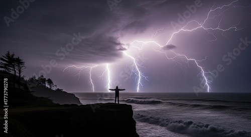 Fototapeta Naklejka Na Ścianę i Meble -  Person with arms outstretched facing a powerful lightning storm over the ocean.