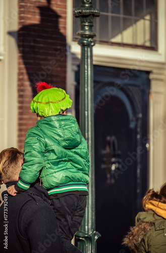 A young child dressed in costume is carried by his father to see Saint Nicholas arrive on his white horse during the festive Sinterklaas celebration in Dordrecht.