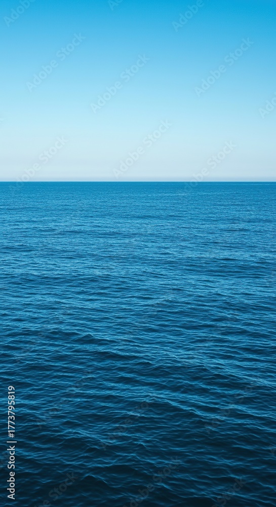 Obraz premium Expansive blue ocean surface stretching towards a distant horizon under a clear sky, showcasing calm yet powerful natural liquid movement ,serene ,vast ,tranquil
