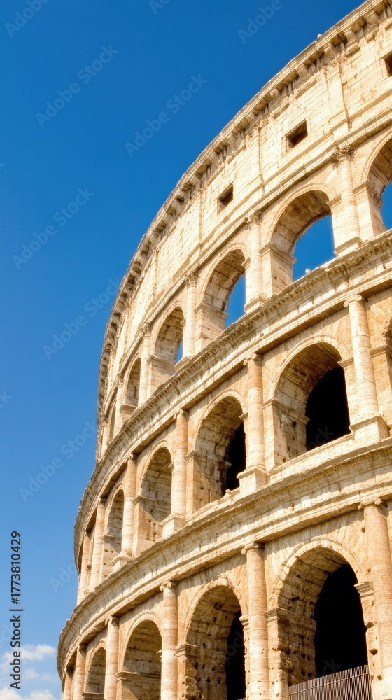 Fototapeta premium The majestic Colosseum rises against the vibrant blue sky, capturing the essence of ancient Rome with an artistic low-angle perspective