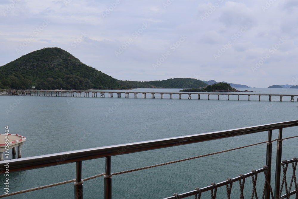 Obraz premium A serene waterside setting with a vast body of water stretching out to the horizon. A pier extends into the water from the foreground, offering a view of a boat dock